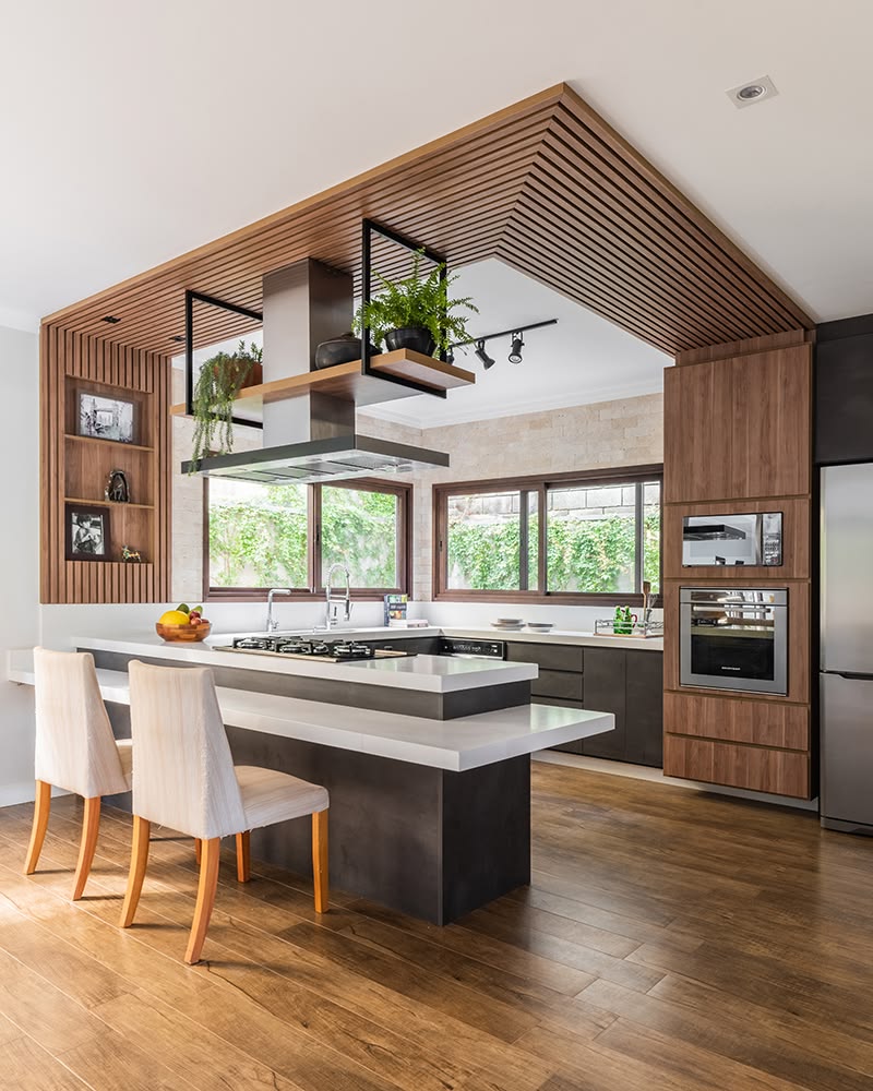 Kitchen with oak cabinetry, slatted breakfast bar, pendant lights and warm under-cabinet lighting